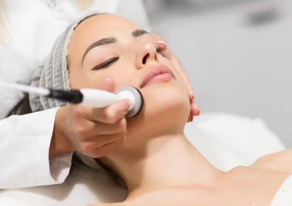 Beautiful young woman getting rejuvenating and tightening skin treatment at professional cosmetic salon.